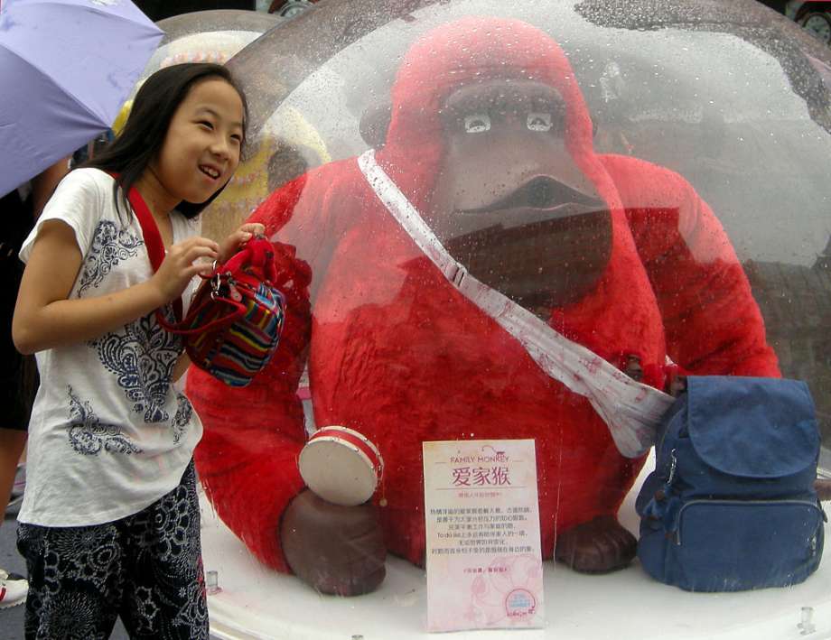 In Beijing, a girl poses with a cartoon monkey in front of Wangfujing department store. The leisure bag brand Kipling's monkey exhibit was a hit with tourists. Photo: Getty Images, Visual China Group / 2016 VCG